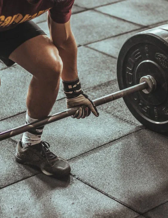 A person lifting a loaded barbell in a gym.