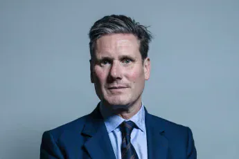 Keir Starmer standing in a blue suit against a plain grey background.