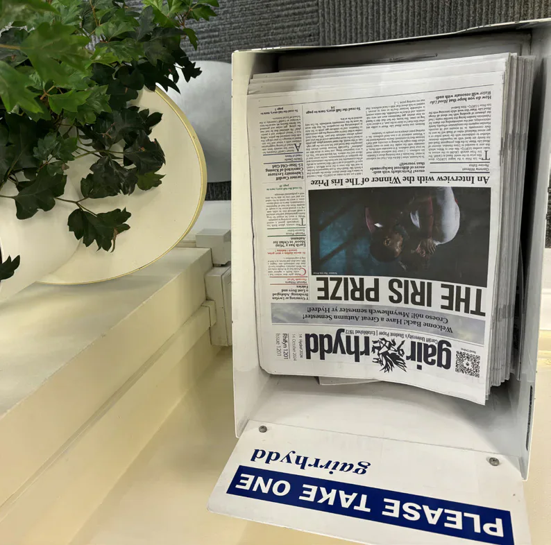 A Gair Rhydd editor seated at the Xpress Radio studio desk.