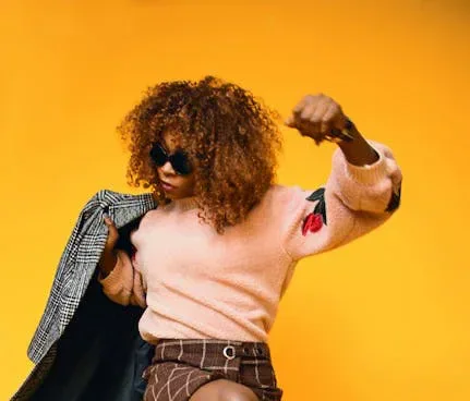 A woman posing in sunglasses against a bright yellow background