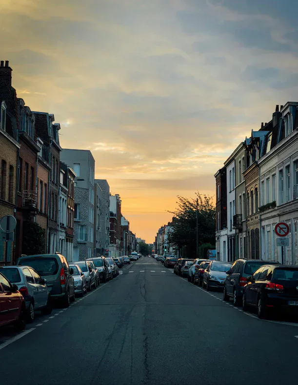 Cars parked along both sides of a residential street at sunset