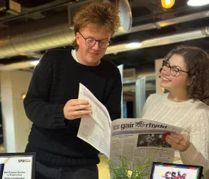 Two student media members reading Gair Rhydd.