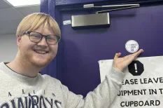 Xpress Radio member holding an award beside a purple door.