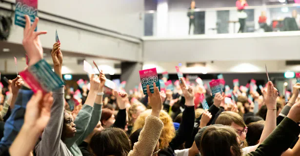 Attendees raising voting cards at a Students’ Union meeting.