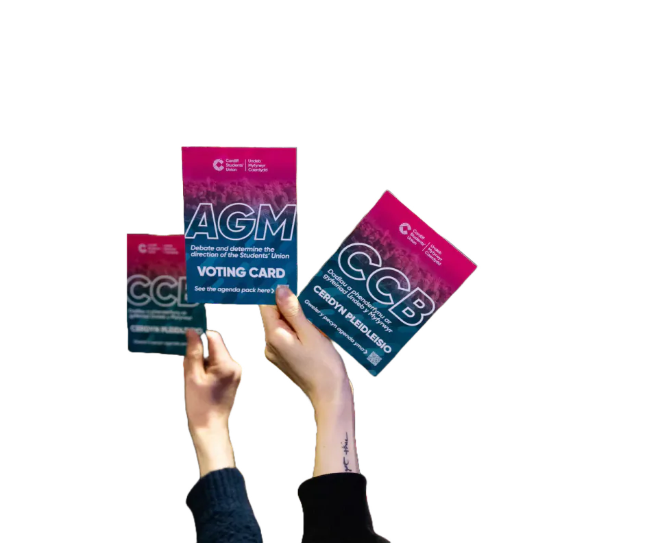 Hands holding bilingual Students’ Union AGM voting cards.