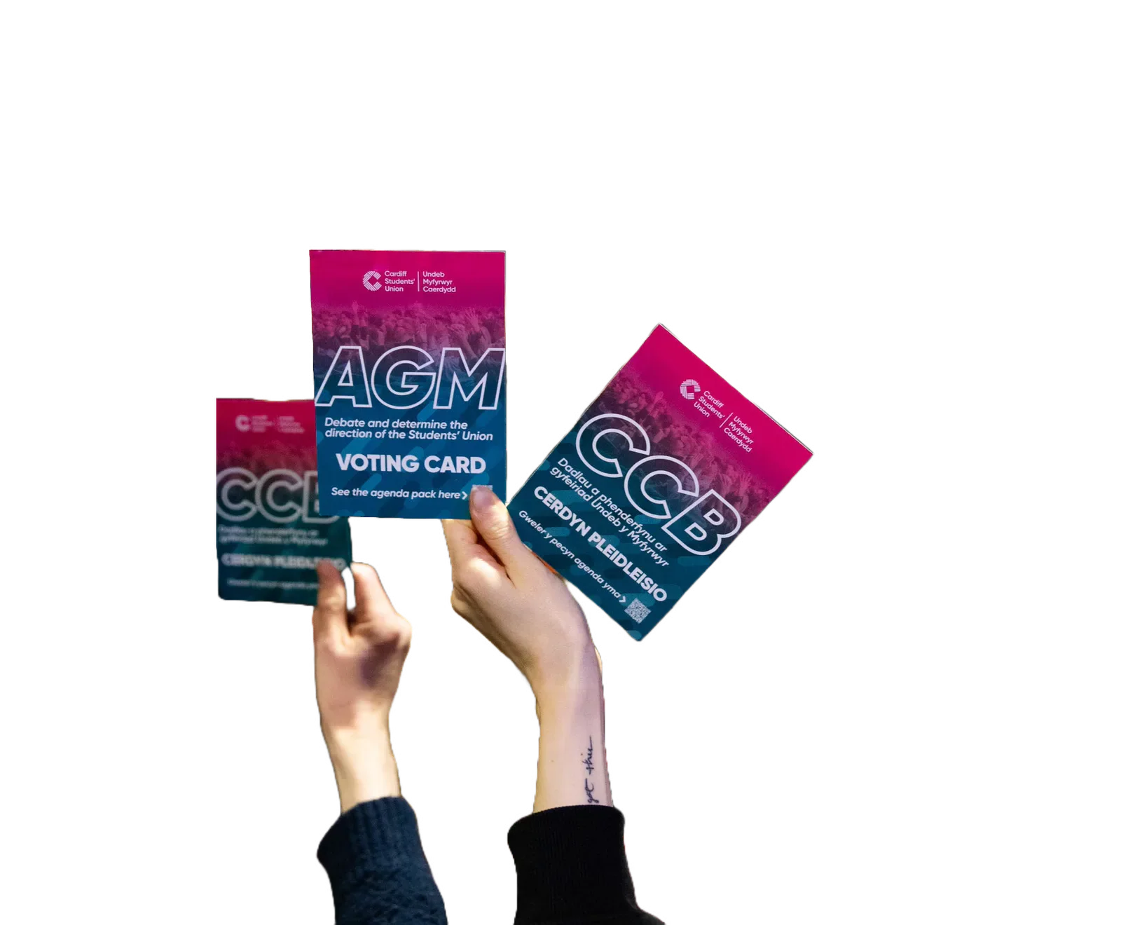 Hands holding bilingual Students’ Union AGM voting cards.