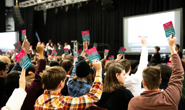 AGM attendees holding voting cards towards the stage.