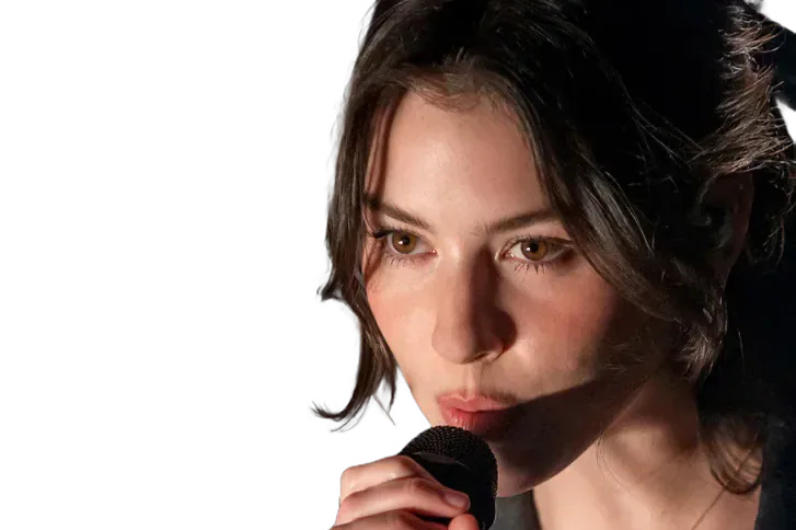 Gracie Abrams singing into a microphone.