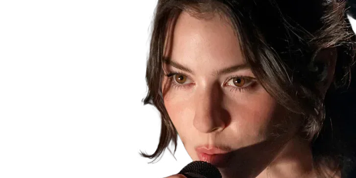 Gracie Abrams singing into a microphone.