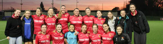 A women’s football team posing together at sunset.
