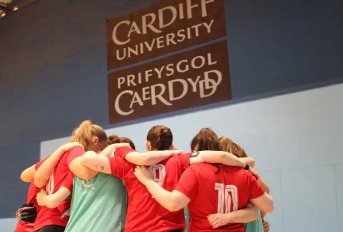 Players huddling beneath a Cardiff University sign.