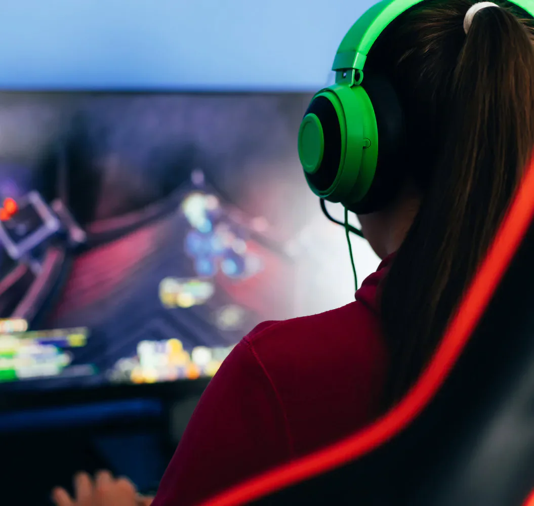 A gamer wearing green headphones in front of a monitor.