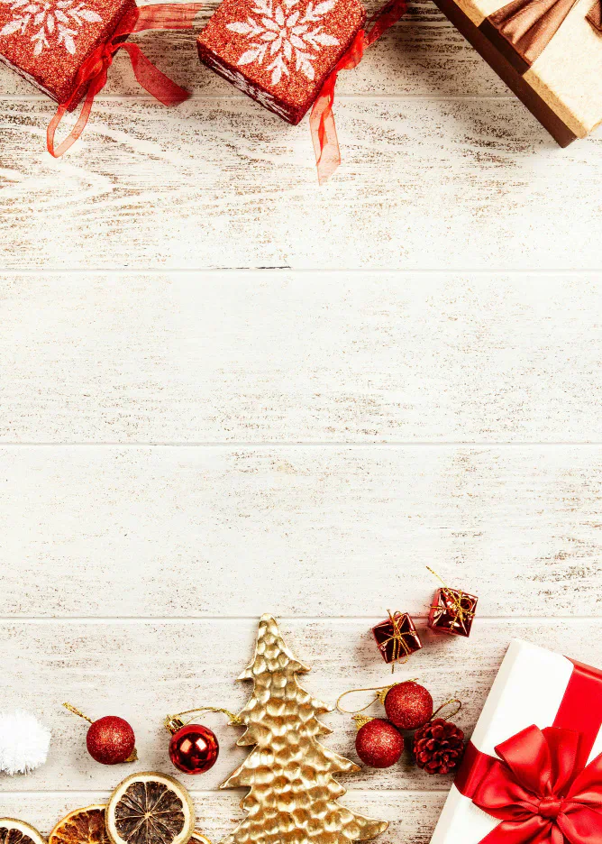 Christmas presents and decorations arranged around a white wooden background.