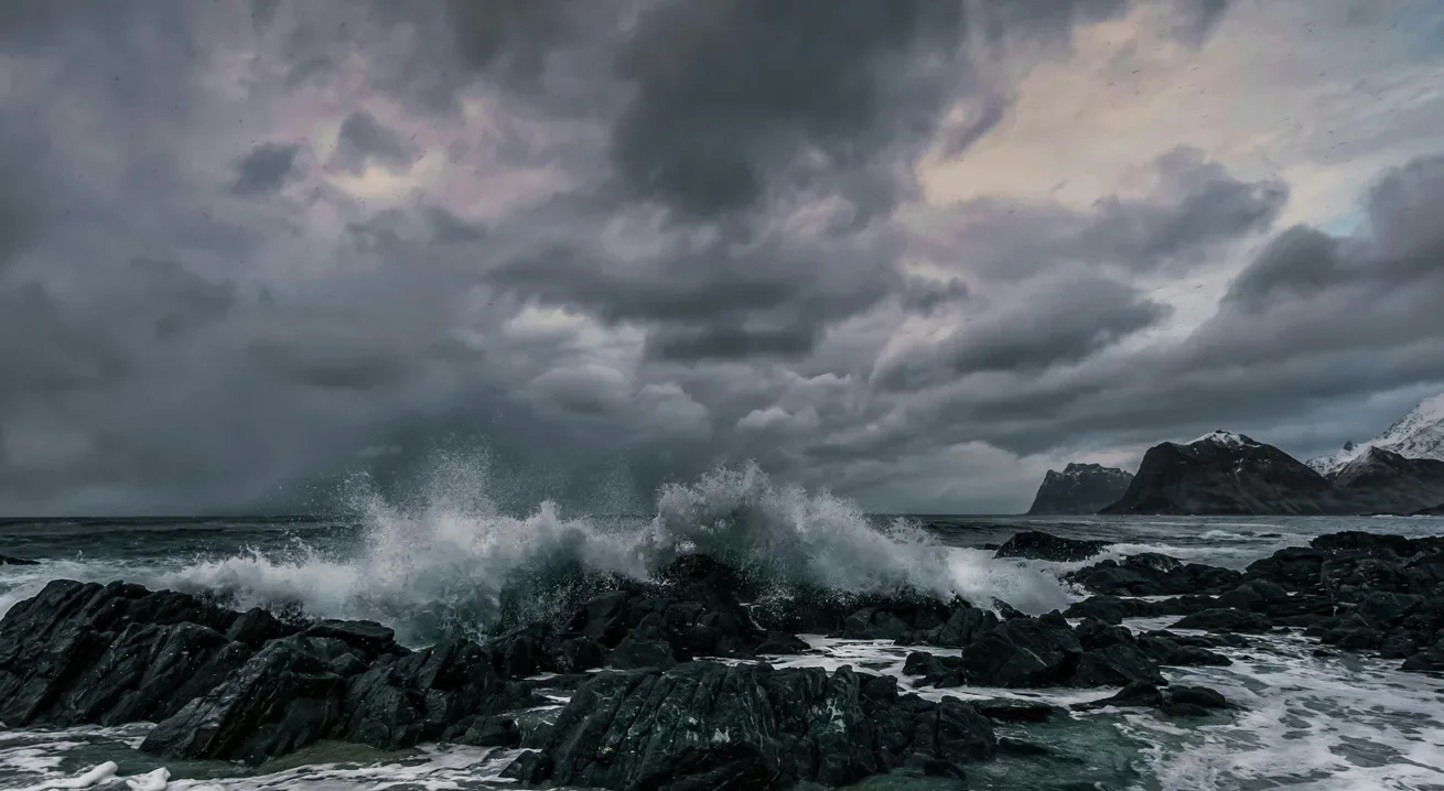 Waves breaking against a rocky coast beneath dark clouds