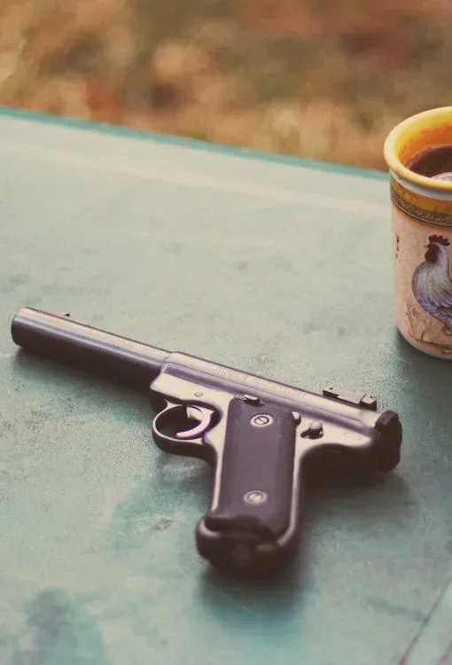 Pistol resting on a table beside a drink