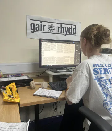 A Gair Rhydd editor working at a desktop computer