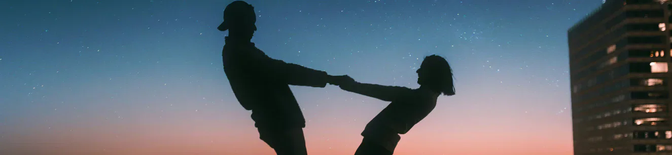 Silhouetted couple holding hands at dusk