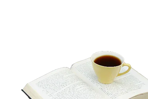 An open book with a cup of coffee resting on its pages.