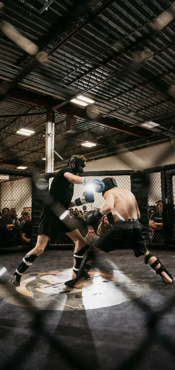 Two mixed martial arts fighters sparring inside a cage.