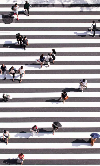 Pedestrians crossing a wide striped road.