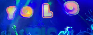 A crowded YOLO club night under ultraviolet lighting.