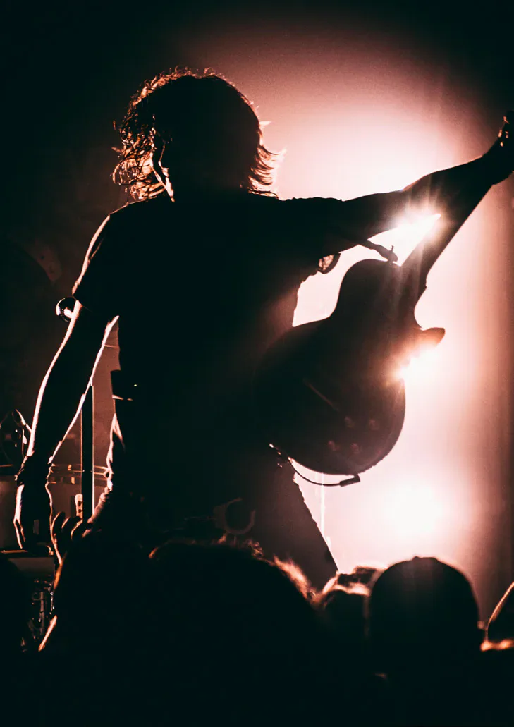 Silhouetted guitarist performing before a crowd
