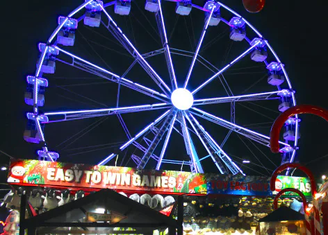 Illuminated Ferris wheel and fairground stalls