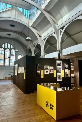 Interior of Ffotogallery with black display walls and a yellow plinth