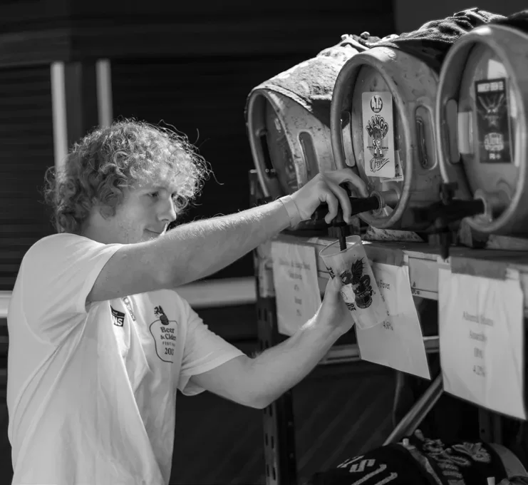 Festival attendee pouring ale from a cask.