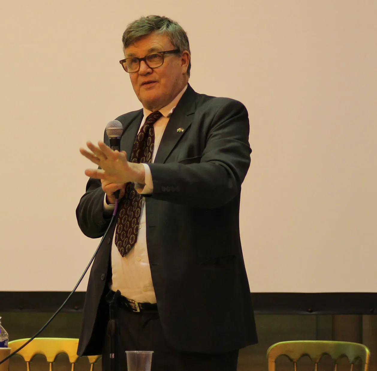 Peter Oborne speaking into a handheld microphone at the Cardiff event.