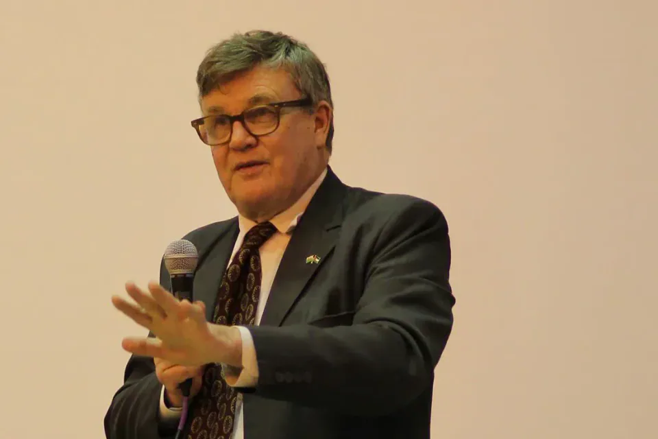 Peter Oborne speaking into a handheld microphone at the Cardiff event.