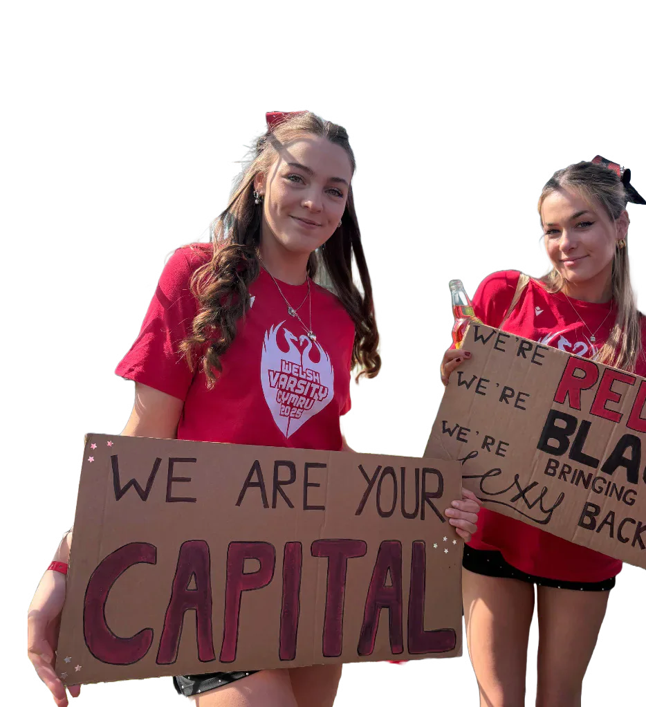 Two Welsh Varsity supporters in red shirts holding handmade signs