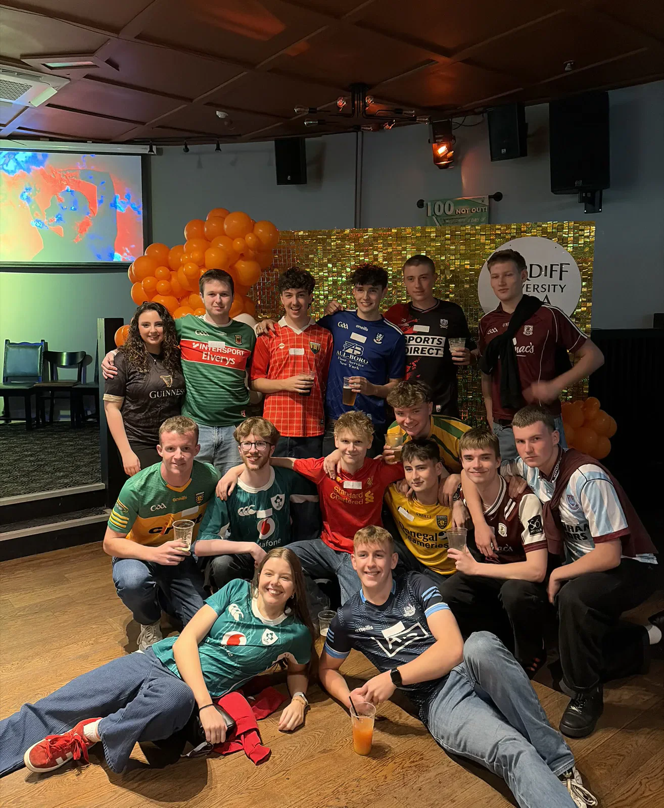 Cardiff University GAA club members in sports shirts gathered for a social event.