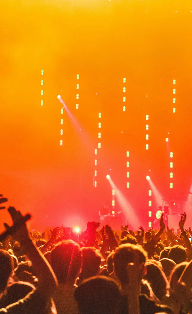 A concert crowd under orange stage lighting