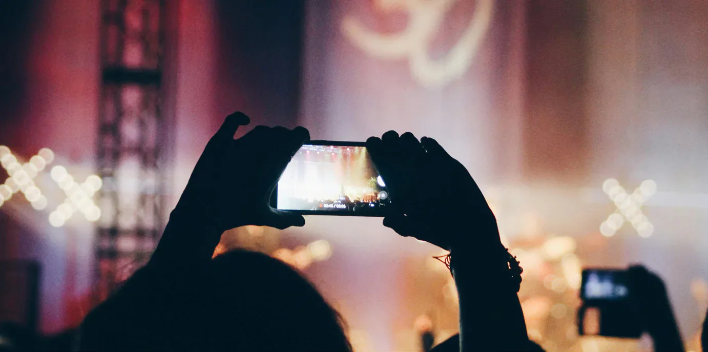 A concertgoer recording a stage on a phone