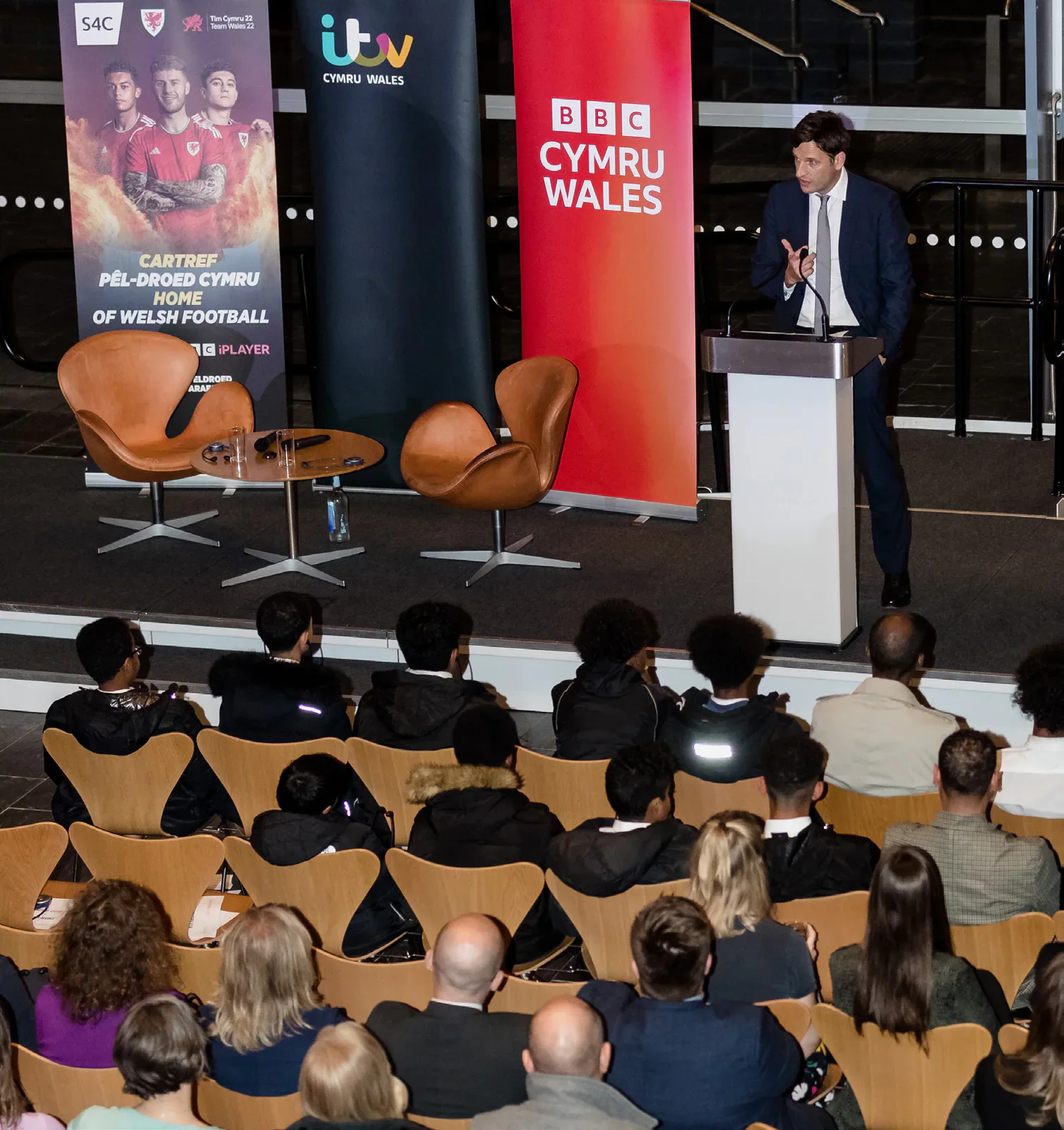 A Welsh football anniversary event with a speaker at a lectern