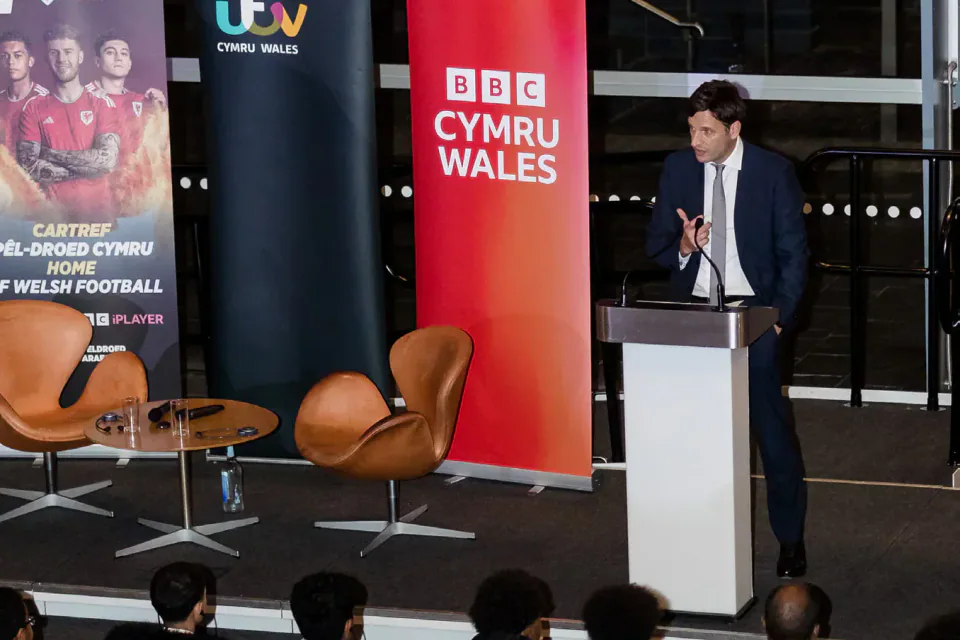 A Welsh football anniversary event with a speaker at a lectern