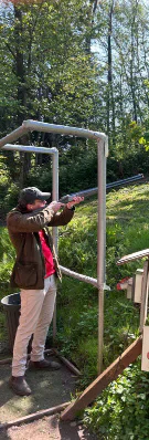 A competitor aims at clay targets from a shooting stand.