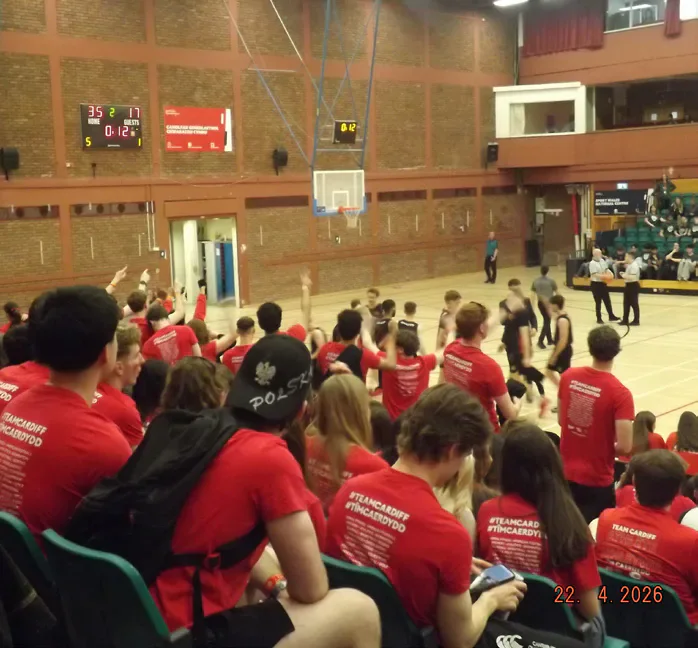 Supporters watch the basketball game from beside the court.