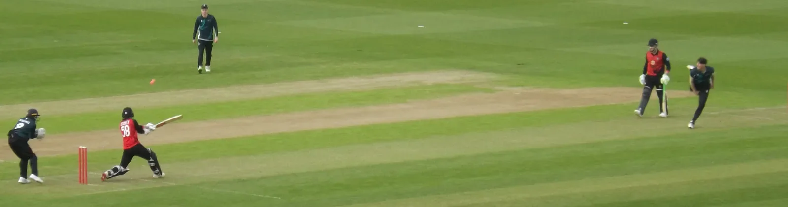 A wide view of a Cardiff batter and Swansea fielders on the cricket pitch.