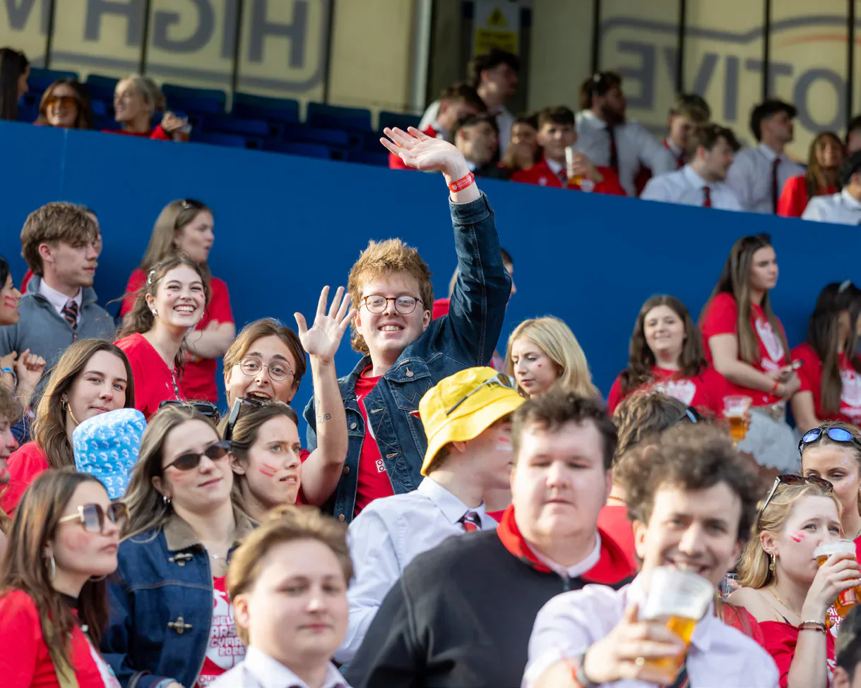 Supporters cheer and wave from the stands.