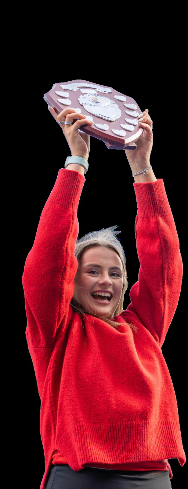 A supporter in a red jumper raises the Varsity shield.