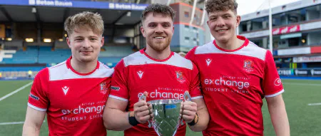 Three Cardiff rugby players hold the Varsity trophy.