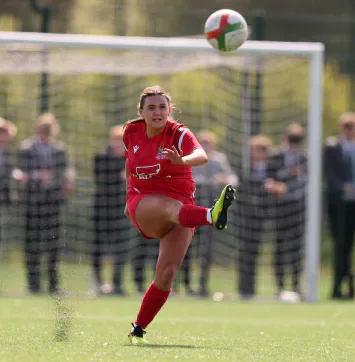 A Cardiff football player strikes the ball in front of the goal.