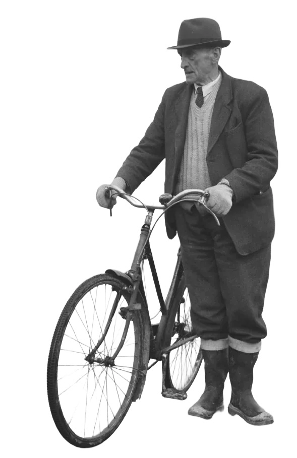 A historical black-and-white photograph of a man standing with a bicycle.