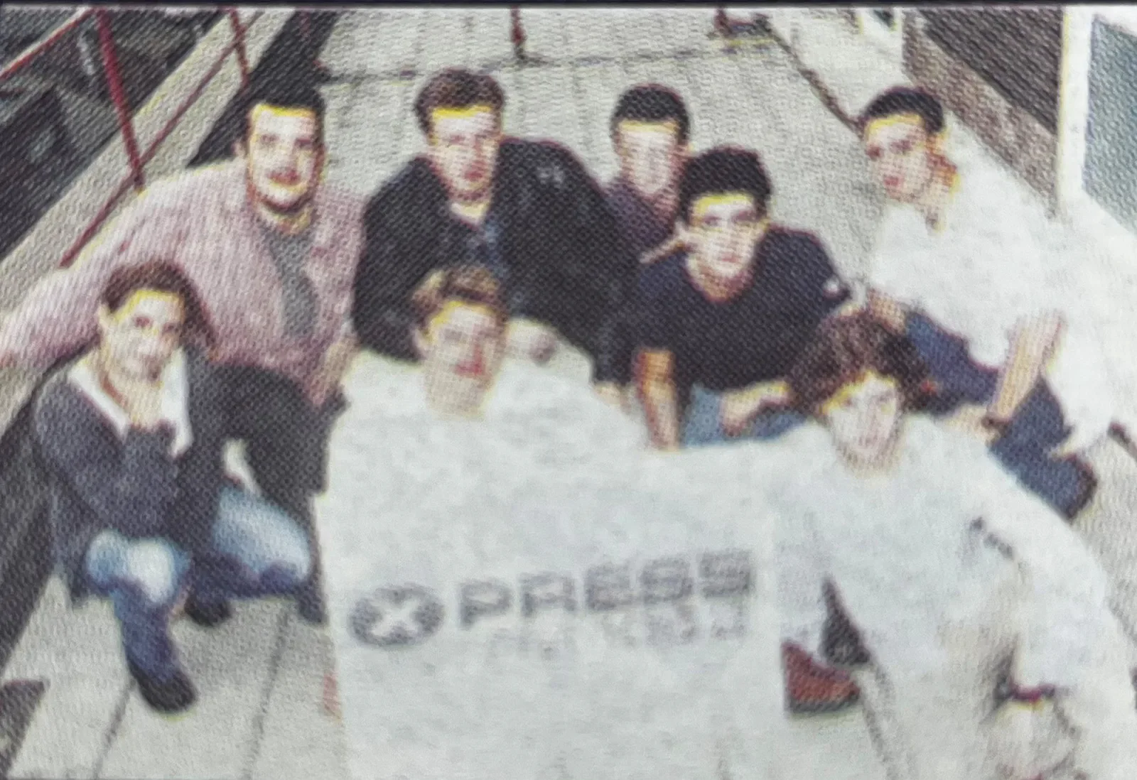 A colour archival group photograph of the Xpress Radio team behind their station banner.