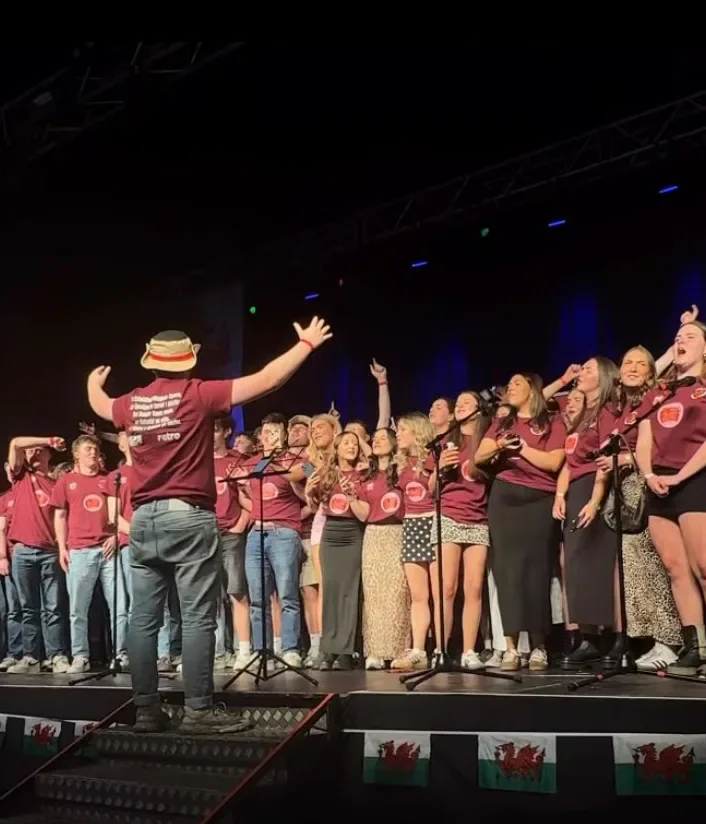 Members of GymGym singing together on stage.