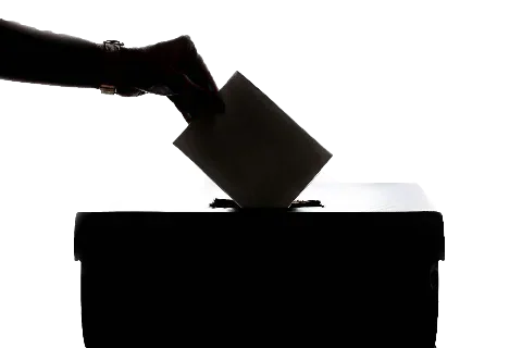 A hand placing a ballot paper into a ballot box.