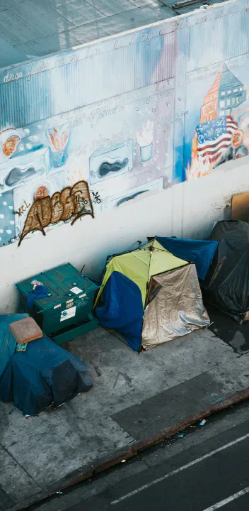 Tents and belongings beneath an urban overpass.