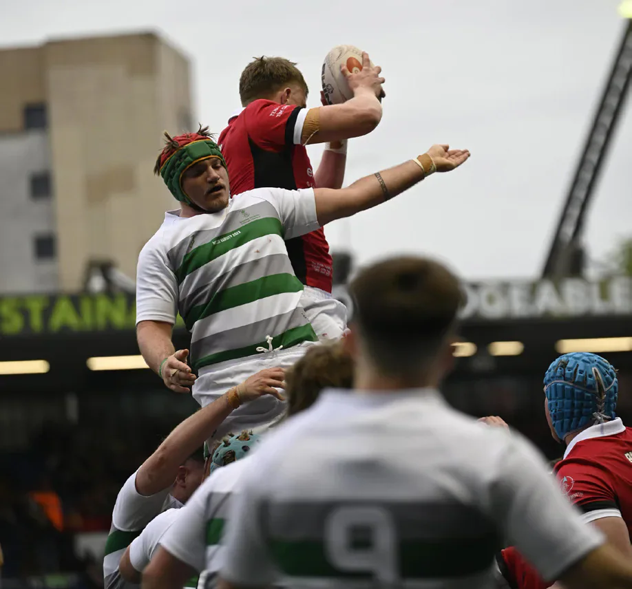 A Cardiff rugby player catches the ball above a Swansea opponent at a lineout.